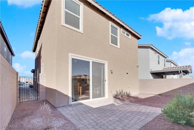 rear view of house featuring a patio area, fence, and stucco siding