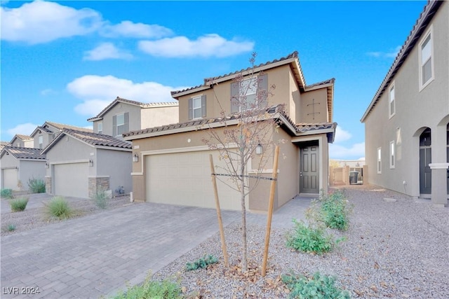 mediterranean / spanish home with cooling unit, a garage, a tile roof, decorative driveway, and stucco siding