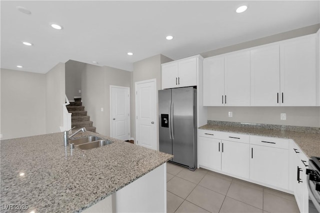 kitchen featuring white cabinets, light stone countertops, stainless steel appliances, and a sink