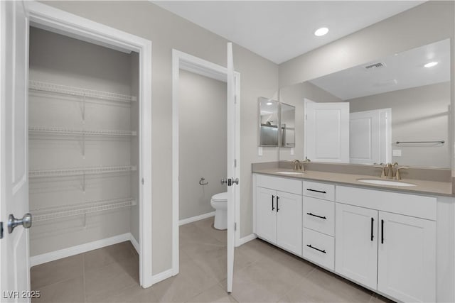 full bath featuring toilet, double vanity, visible vents, and a sink