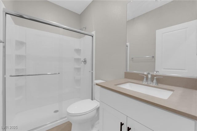 full bathroom with vanity, a shower stall, and toilet