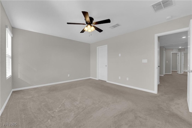 empty room with baseboards, visible vents, ceiling fan, and carpet flooring