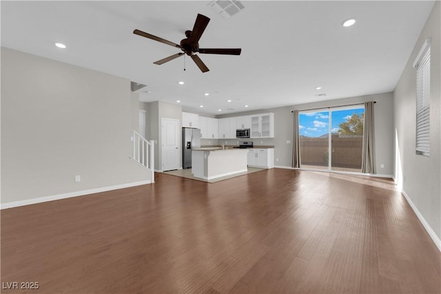 unfurnished living room with baseboards, visible vents, stairway, wood finished floors, and recessed lighting