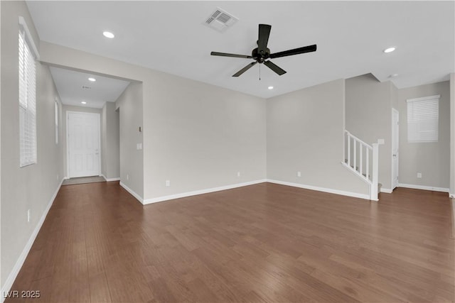 empty room with stairway, baseboards, visible vents, and wood finished floors