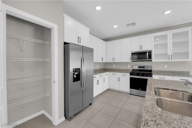 kitchen with stainless steel appliances, a sink, visible vents, white cabinetry, and light stone countertops