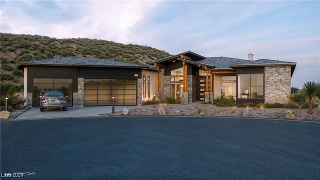 view of front of property featuring a garage, stone siding, a chimney, and concrete driveway