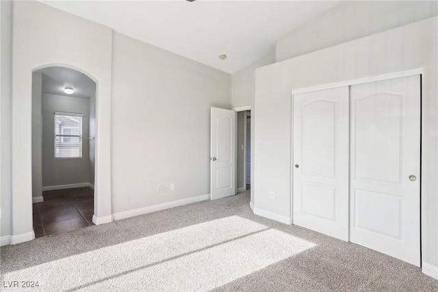 unfurnished bedroom with carpet, vaulted ceiling, and a closet