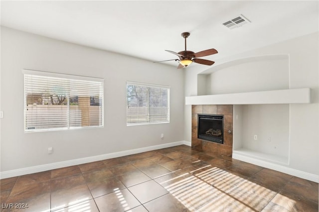 unfurnished living room featuring a tile fireplace and ceiling fan