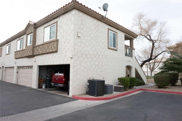 view of property exterior with a garage and central air condition unit