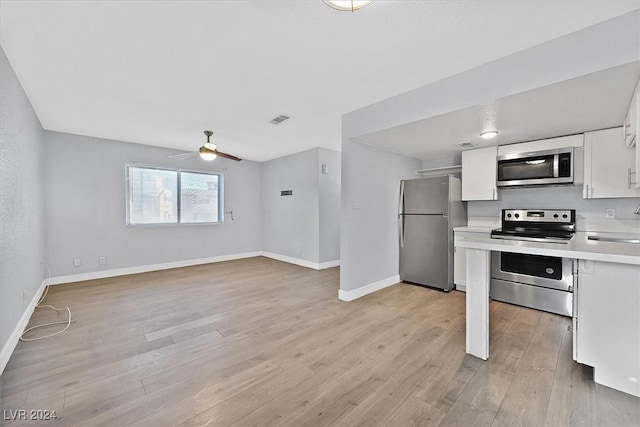 kitchen featuring ceiling fan, white cabinets, stainless steel appliances, and light wood-type flooring