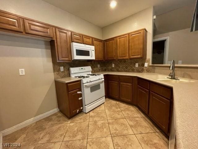 kitchen featuring tasteful backsplash, sink, light tile patterned floors, and white appliances