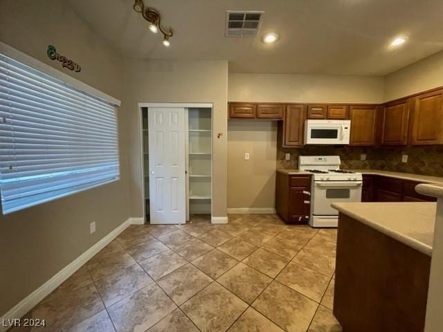 kitchen featuring light tile patterned flooring, white appliances, and backsplash