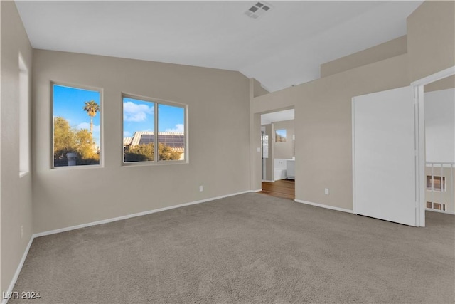 carpeted empty room featuring lofted ceiling