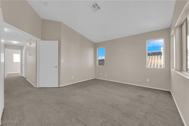 carpeted spare room with lofted ceiling