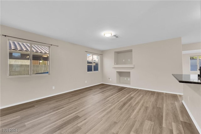 unfurnished living room with light hardwood / wood-style floors and a healthy amount of sunlight