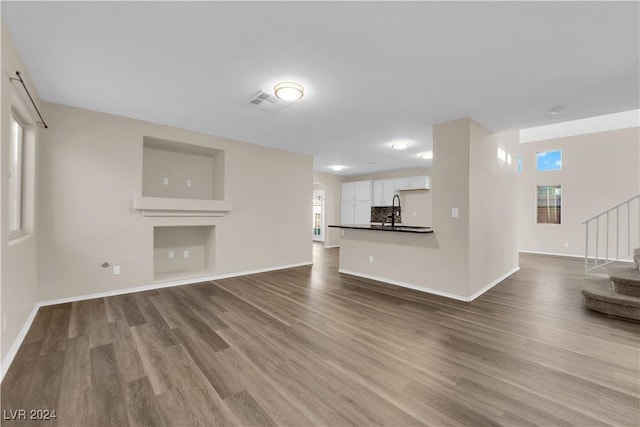 unfurnished living room with plenty of natural light, wood-type flooring, and sink