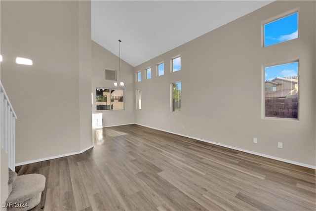 unfurnished living room with plenty of natural light, a towering ceiling, and wood-type flooring