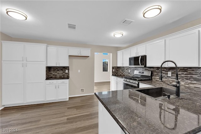 kitchen featuring white cabinets, appliances with stainless steel finishes, sink, and dark stone countertops