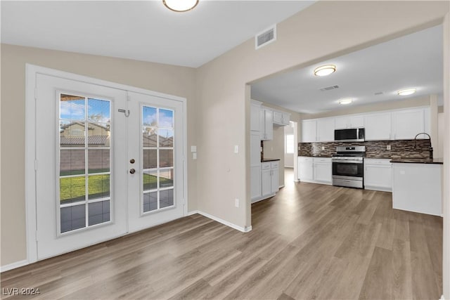 kitchen with backsplash, french doors, light wood-type flooring, white cabinetry, and stainless steel appliances