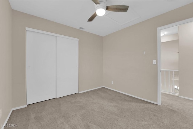 unfurnished bedroom with ceiling fan, light carpet, and a closet