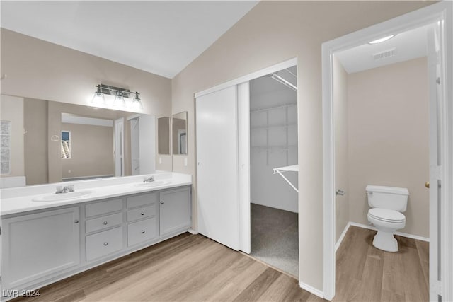 bathroom with hardwood / wood-style floors, vanity, toilet, and vaulted ceiling