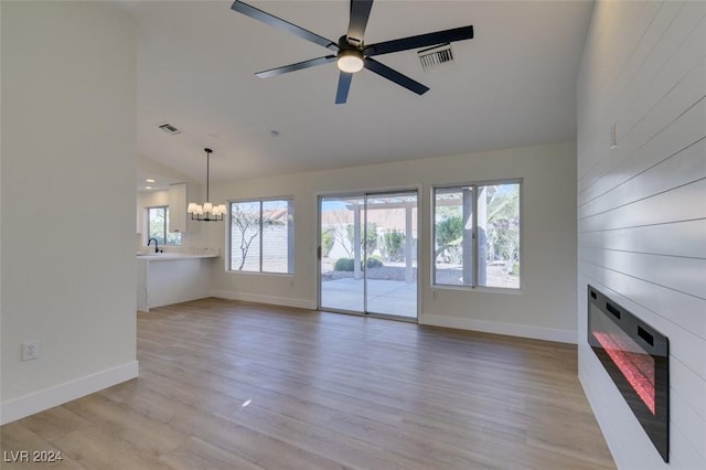 unfurnished living room featuring ceiling fan with notable chandelier, light hardwood / wood-style floors, vaulted ceiling, and sink