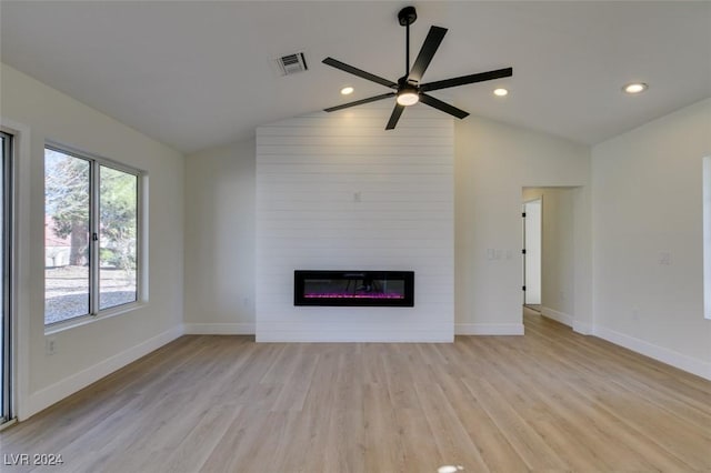 unfurnished living room with ceiling fan, a large fireplace, vaulted ceiling, and light hardwood / wood-style flooring