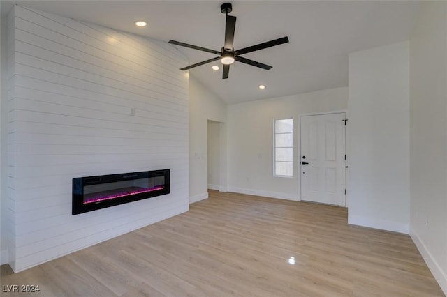 unfurnished living room with light wood-type flooring, a large fireplace, ceiling fan, and lofted ceiling