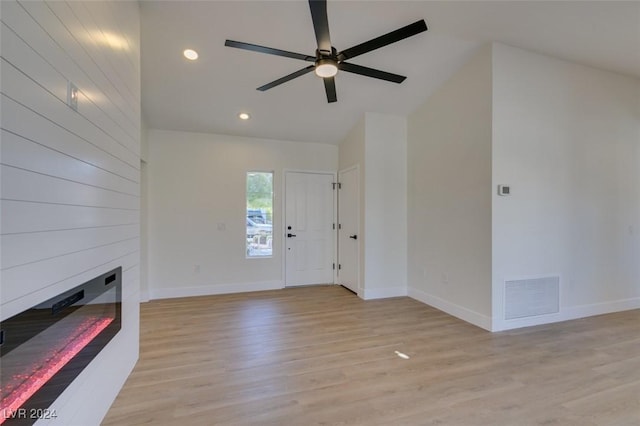 unfurnished living room featuring ceiling fan, a fireplace, lofted ceiling, and light wood-type flooring