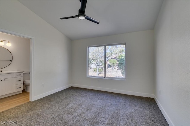 unfurnished bedroom featuring connected bathroom, light colored carpet, vaulted ceiling, and ceiling fan