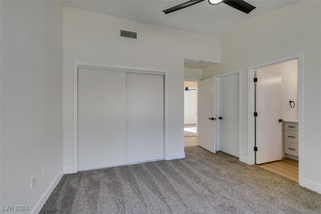 unfurnished bedroom featuring ceiling fan, a closet, ensuite bathroom, and light colored carpet