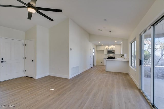 unfurnished living room with ceiling fan with notable chandelier, light wood-type flooring, lofted ceiling, and sink