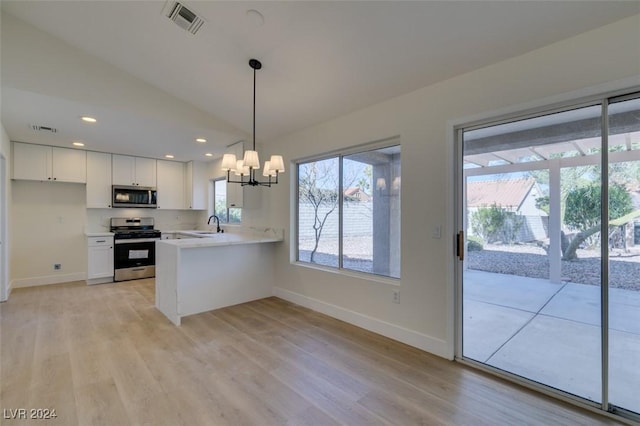 kitchen featuring white cabinetry, kitchen peninsula, decorative light fixtures, appliances with stainless steel finishes, and light wood-type flooring