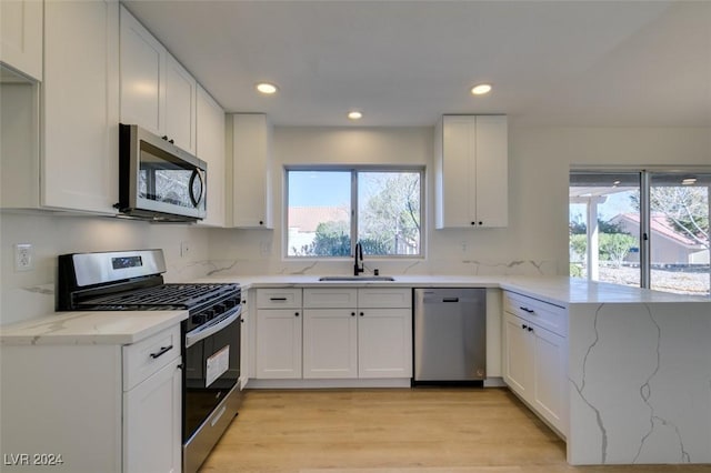 kitchen featuring white cabinets, light stone counters, sink, and stainless steel appliances