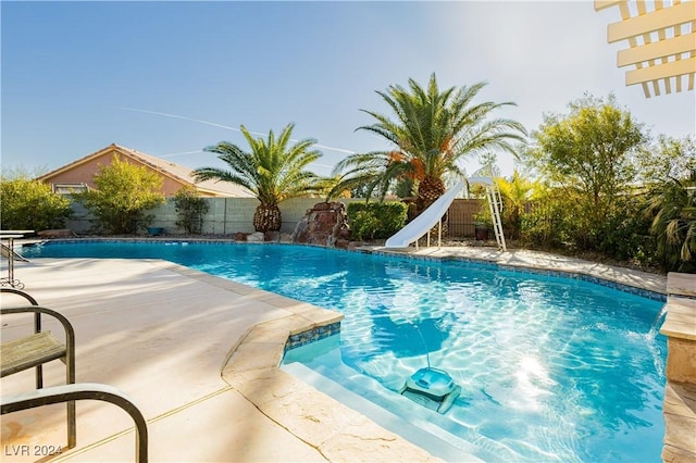 view of swimming pool with pool water feature, a water slide, and a patio