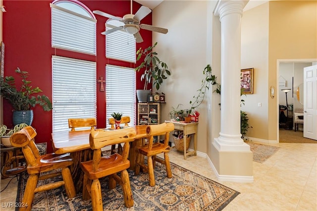 dining room with light tile patterned floors, a towering ceiling, ornate columns, and ceiling fan