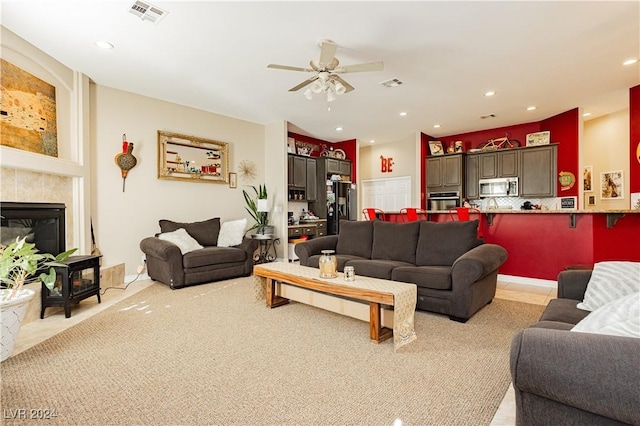 carpeted living room with ceiling fan and a fireplace