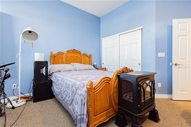 carpeted bedroom featuring a wood stove and a closet