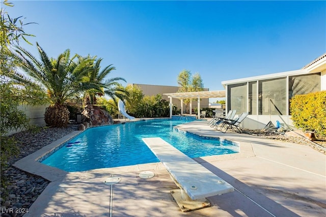 view of swimming pool with a sunroom, a diving board, a water slide, a pergola, and a patio area