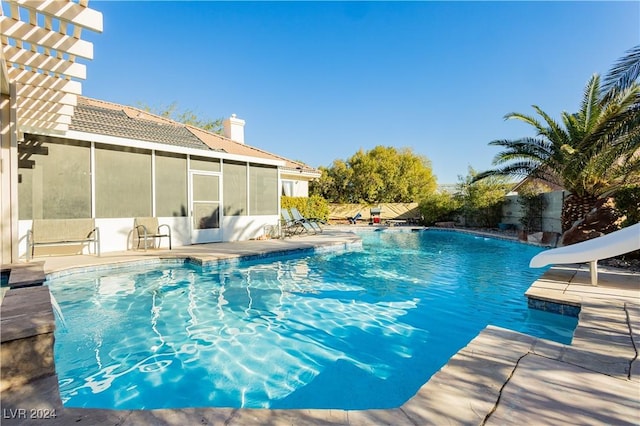 view of swimming pool featuring a sunroom and a water slide