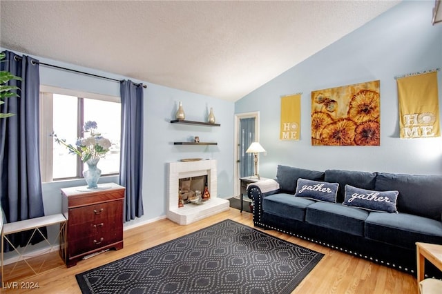 living room with lofted ceiling, light wood-type flooring, and a brick fireplace