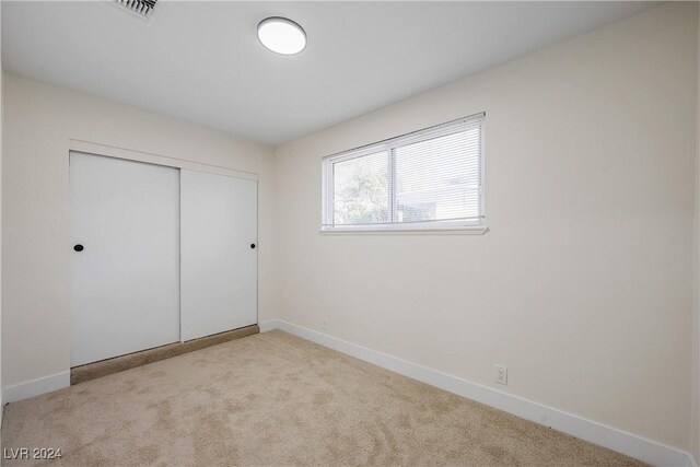 unfurnished bedroom featuring a closet and light colored carpet