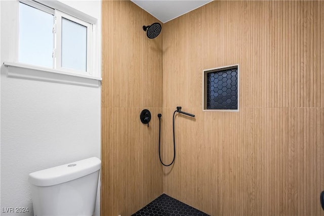 bathroom with a tile shower and toilet