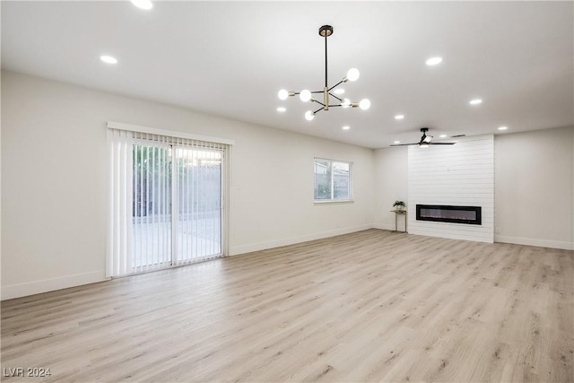 unfurnished living room with a large fireplace, ceiling fan with notable chandelier, and light hardwood / wood-style floors