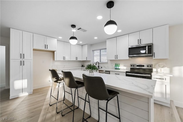 kitchen with pendant lighting, white cabinetry, a center island, and stainless steel appliances