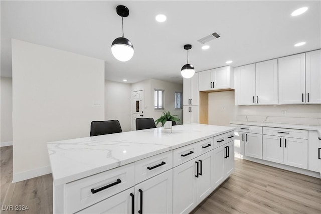 kitchen with light stone countertops, decorative light fixtures, white cabinetry, light hardwood / wood-style floors, and a kitchen island