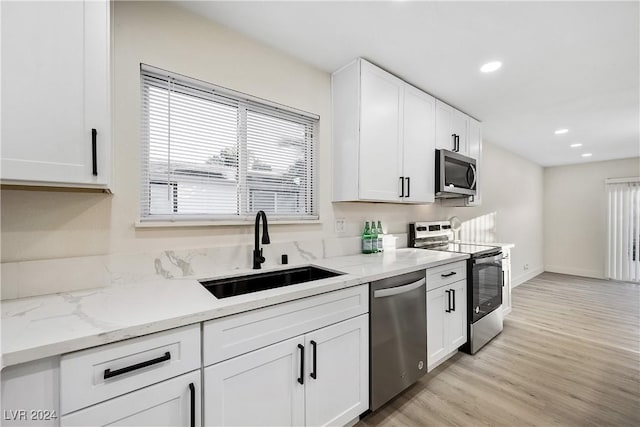 kitchen featuring light stone counters, stainless steel appliances, sink, light hardwood / wood-style flooring, and white cabinets