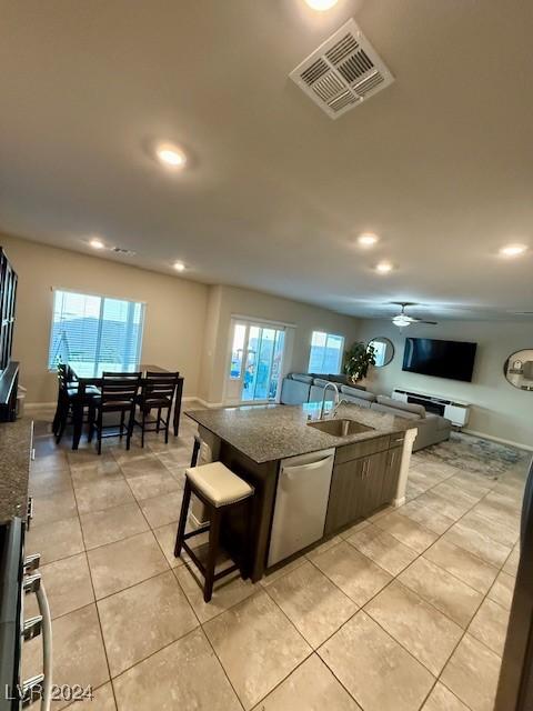 kitchen featuring sink, light tile patterned floors, stainless steel dishwasher, plenty of natural light, and a kitchen island with sink