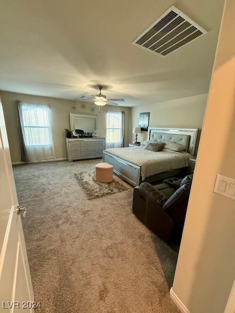 bedroom featuring ceiling fan, multiple windows, and carpet