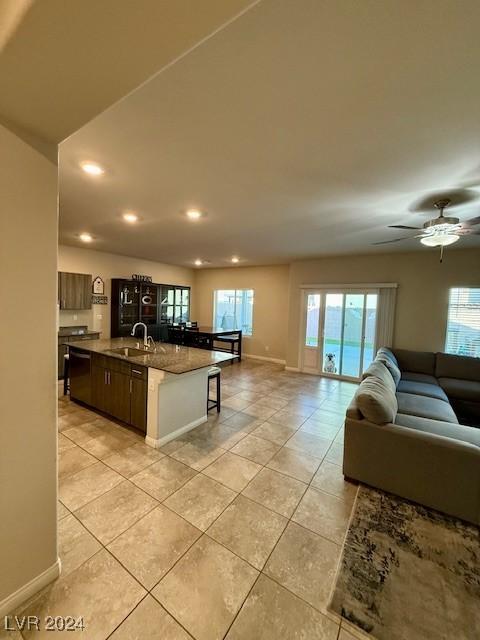 kitchen with sink, dark brown cabinets, a center island with sink, light tile patterned floors, and a kitchen breakfast bar